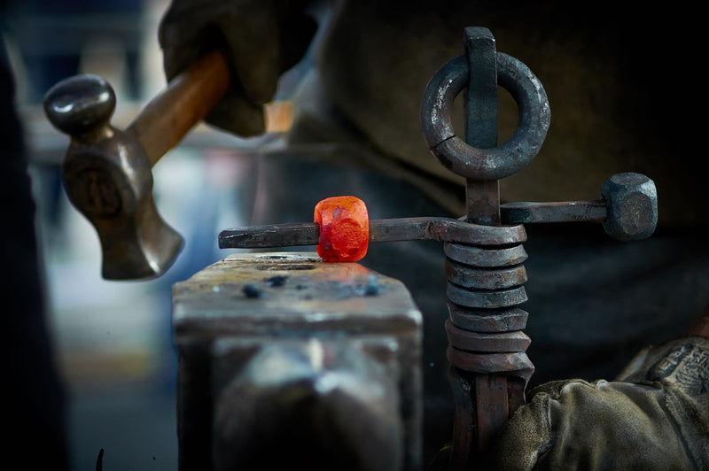 Blacksmith hammering hot steel into shape on an anvil