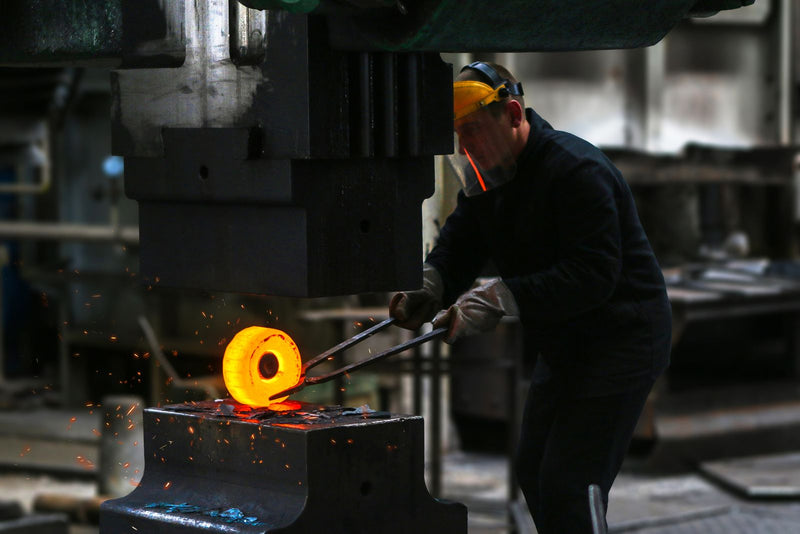 Blacksmith working red-hot steel with tongs